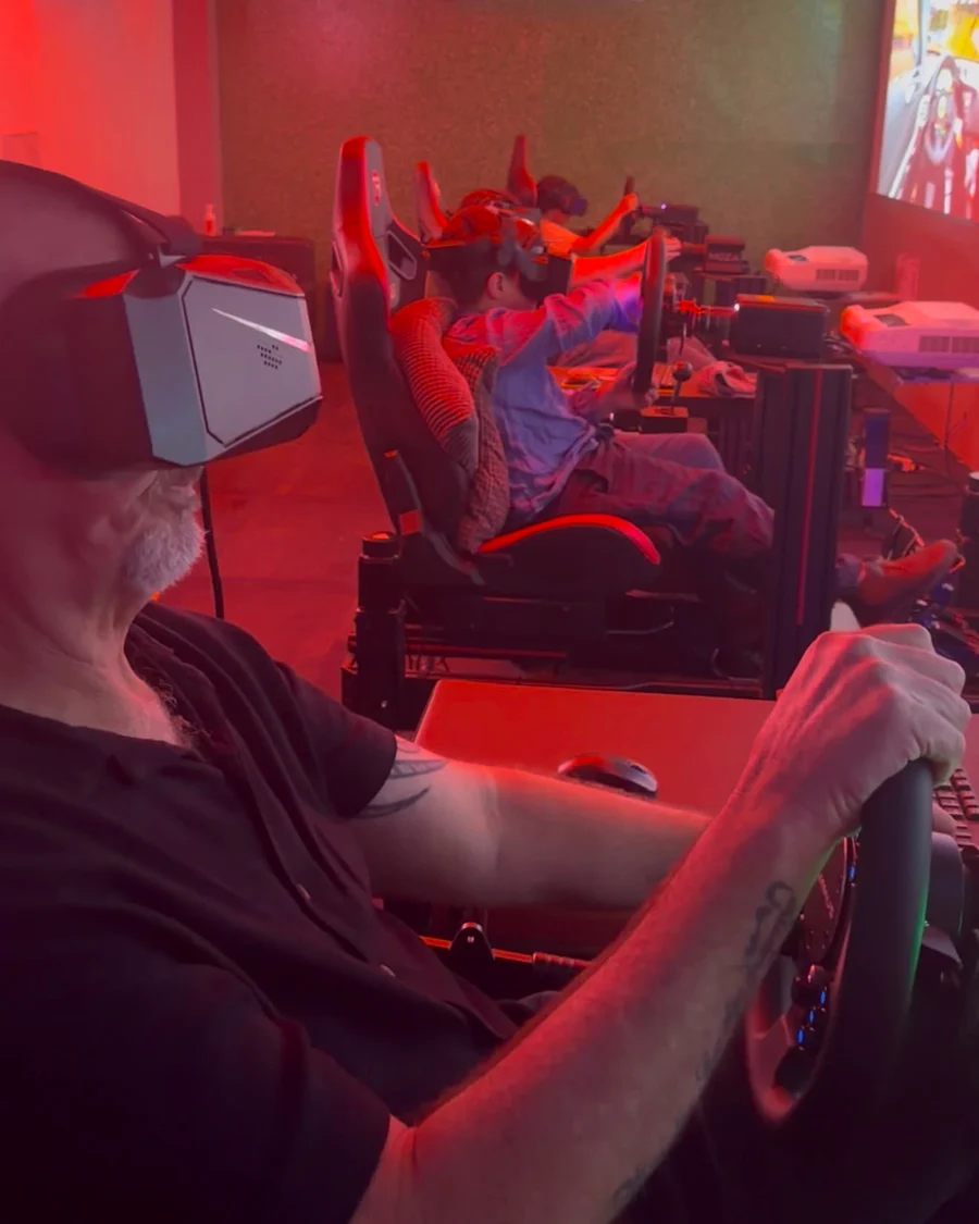 A dad in the VR simulator with his family racing behind him at Sim Racing Adelaide